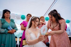 Candid moment of wedding guests in elegant dresses during outdoor tent reception.