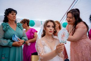 Wedding guests in formal attire socialize during tented outdoor celebration.