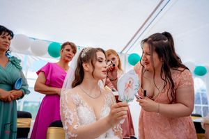 Guests enjoying a special moment at a wedding reception under a white tent with teal accents.