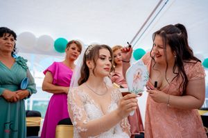 Wedding reception candid moment with guests in pink and teal dresses under a white tent.