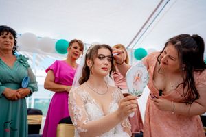 Wedding party members sharing laughs during reception under decorated white tent.