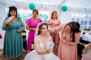 Wedding celebration in a tent decorated with teal balloons and string lights.