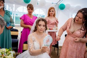 Wedding party gathered for candid moments during reception under white tent with teal decor.