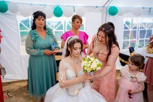 Festive wedding reception under white tent with teal balloons and decorative lighting.