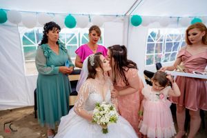Intimate moment shared during wedding celebration under white tent with teal decorations.