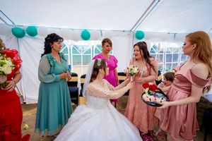 Festive wedding reception scene with bridal party enjoying refreshments under decorated tent.