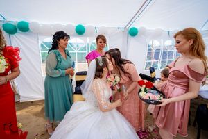 Candid wedding moment captured during reception under white tent with teal accents.