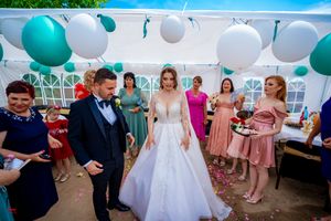 Wedding celebration under tent decorated with teal and white balloons showing bridal party.