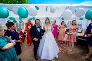 Joyous wedding celebration with teal and white balloon decor under outdoor tent.