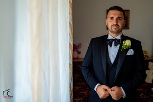 Groom in classic black tuxedo making final adjustments before ceremony.