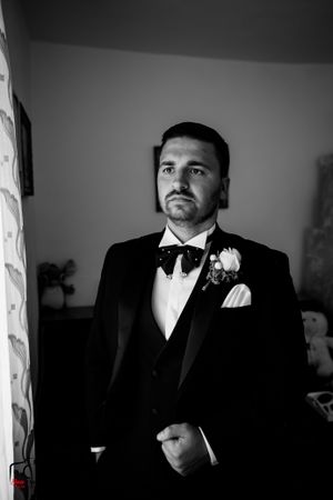 Black and white portrait of groom in formal attire with dramatic lighting.