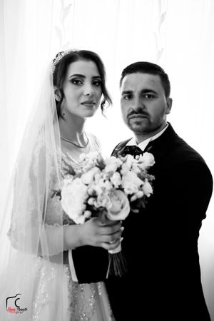 An artistic black and white wedding portrait featuring a couple with a white bouquet.