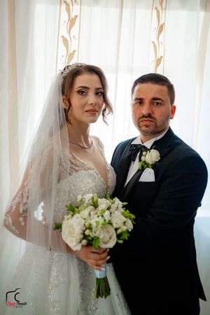 A romantic wedding photoshoot with the couple posing against white curtains with natural lighting.