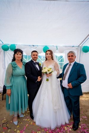Wedding group photos being taken under a white tent decorated with teal balloons.