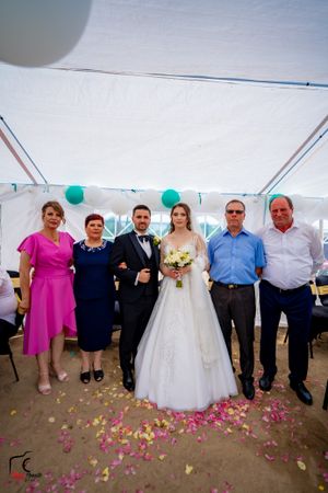 Wedding celebration inside a tent with guests in formal wear and bright pink and blue outfits.