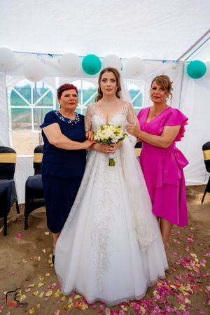 Wedding group photo showing guests in formal attire with scattered flower petals on the ground.