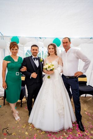 Wedding celebration in a white tent with guests gathered around the bride in a white gown.