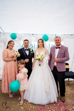 Wedding celebration showing guests in formal attire with teal balloons and pink floral decorations.