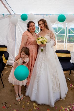 Wedding photos showing bride in white gown with guests wearing pink dresses under decorated tent.