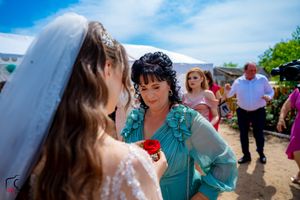 Emotional wedding moment captured during outdoor celebration under bright blue sky.