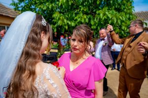 Wedding guests celebrate outdoors on a sunny day with bright smiles and festive attire.