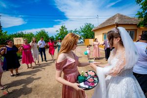 Wedding party celebrates outside a yellow building on a bright sunny afternoon.