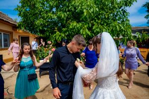Outdoor wedding reception with guests in formal attire enjoying festivities near a building.