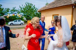 Guests throw confetti during outdoor wedding celebration near a yellow building.