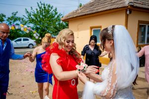 Wedding party throws confetti in celebration outside a rustic yellow building.