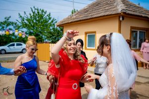 Festive outdoor wedding scene with guests throwing confetti near a yellow building.