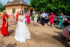 Wedding guests dance in a line at an outdoor celebration with colorful dresses and festive atmosphere.