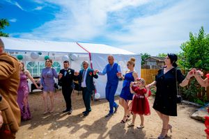 Panoramic view of wedding celebration with guests dancing in formation under blue skies.