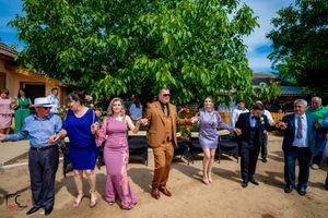 Party guests in formal attire dancing in formation during an outdoor celebration.