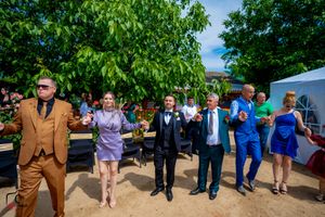 Formal-dressed guests performing synchronized dance moves at an outdoor party.