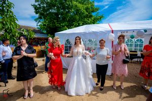 Wedding celebration outdoors with guests gathered under a white tent on a sunny summer day.