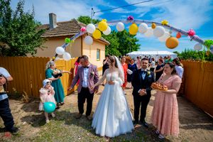 Outdoor wedding celebration with guests enjoying festivities under decorated balloon archway.