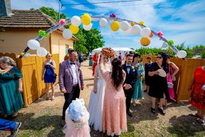 Festive outdoor party scene with yellow and white balloons decorating a sunny courtyard.