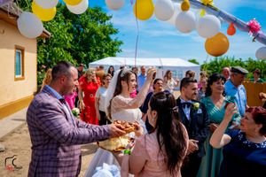 Wedding celebration outdoors with yellow and white balloon arch decorations and guests gathered for a traditional ceremony.