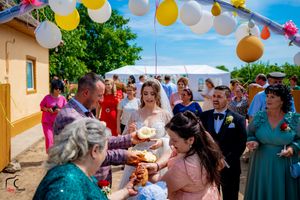 Festive outdoor wedding gathering under balloon arch with guests celebrating and sharing traditional customs.