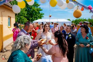 Joyful wedding celebration under decorative balloon arch with guests participating in traditional customs.