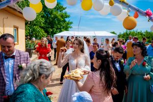 Wedding party gathered outdoors under festive balloon arch during traditional ceremony customs.