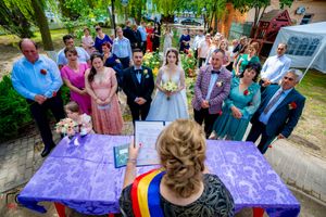 Wedding celebration with purple tablecloth and guests gathered in a garden setting.