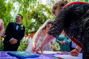Guests watching as documents are signed during an outdoor wedding celebration.