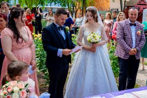 Wedding guests gather under a weeping willow tree for an outdoor celebration ceremony.
