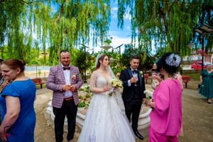 Wedding group gathered outdoors beneath cascading willow trees for photos.