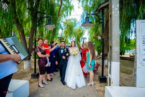 Stone pathway lined with celebrating guests under the canopy of weeping willow trees.