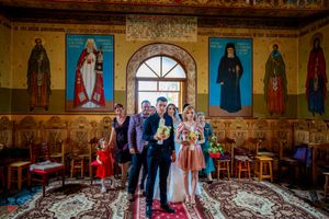 Orthodox wedding ceremony taking place in an ornate church with gilded walls and religious iconography.