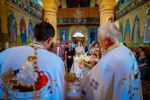 Traditional Orthodox Christian wedding service with clergy in white robes performing sacred rituals.