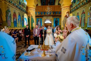 Religious ceremony in a Byzantine-style church with golden columns and painted saints on the walls.