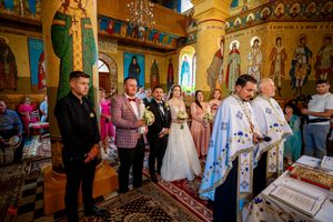 Religious ceremony being conducted in an ornate Orthodox church with Byzantine-style decorations.